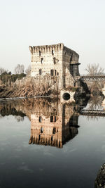 Old building by lake against sky