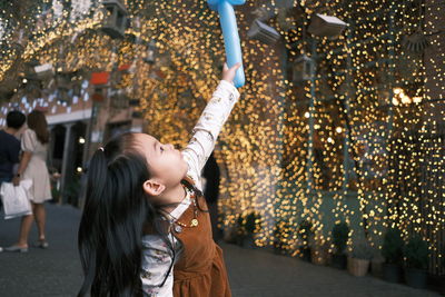 Portrait of happy girl standing in illuminated traditional clothing