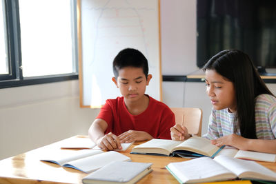 Asian boy girl student studying doing homework in library. learning education at school