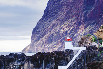 Scenic view of sea by mountain against sky