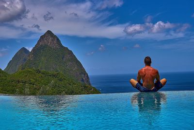 Man on rock by sea against sky