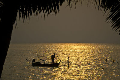 Silhouette of a fisherman in a boat at sunset in the gulf of thailand off the coast of koh samui. 