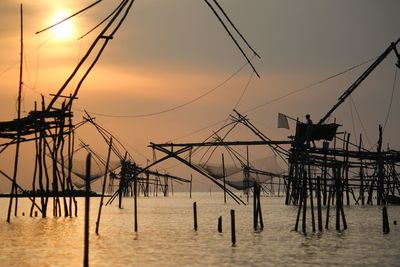 Silhouette man fishing in sea against sky during sunset