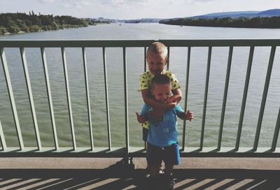 Portrait of boy standing by railing against lake