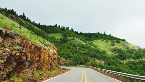 Winding road passing through lush foliage mountain