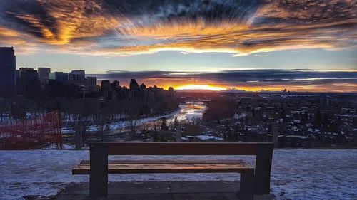 Scenic view of city during winter against sky at sunset