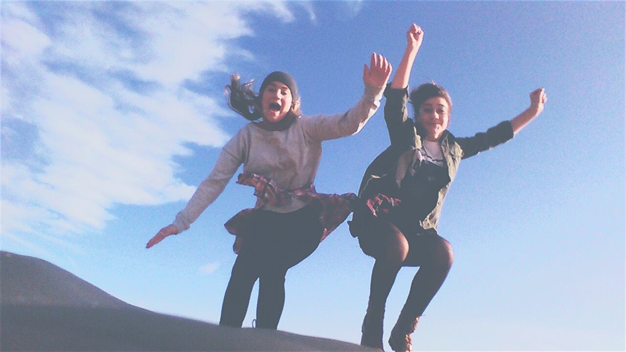 lifestyles, leisure activity, person, fun, happiness, full length, togetherness, enjoyment, young adult, sky, casual clothing, low angle view, young men, mid-air, bonding, front view, arms raised