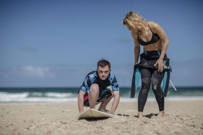 Teenage boy with down syndrome having surf lessons on beach