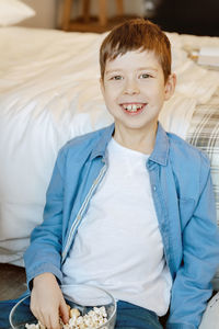 Portrait of smiling boy sitting on bed