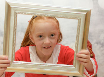 Portrait of smiling girl holding frame