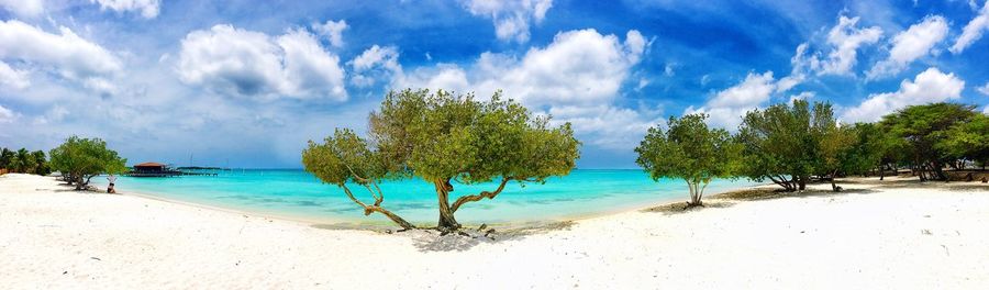 Panoramic view of calm beach against cloudy sky