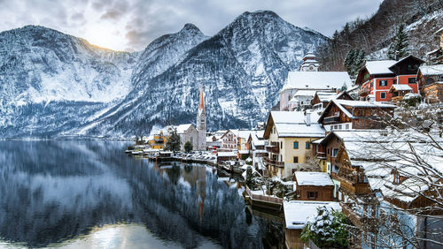 Houses by lake against mountains at hallstatt in winter