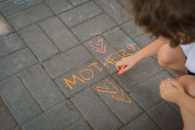 Cute boy draws the word mother with chalk. the boy loves his mother.