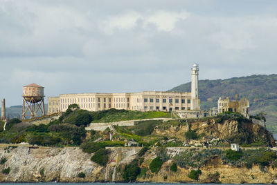 Lighthouse by prison at alcatraz island against sky