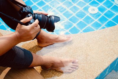 Low section of man photographing in swimming pool