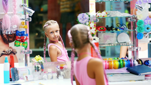 Beautiful blond girl, of seven years old, braided two pigtails, do a hairstyle with pink locks of