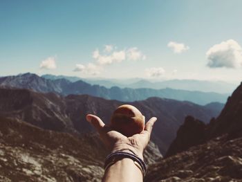 Cropped hand holding fruit against mountain