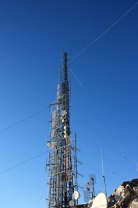 Low angle view of communications tower against blue sky