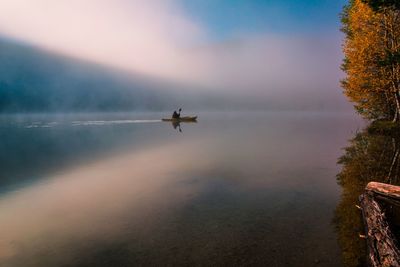 Airplane flying over sea against sky during sunset