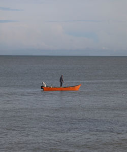 Man kayaking on sea against sky