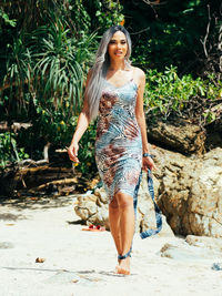 Portrait of young trans woman standing against rock