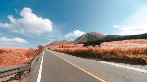 Road leading towards mountain against sky