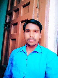 Portrait of young man standing against blue wall