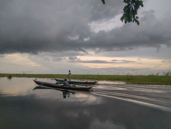 Man on boat against sky during sunset