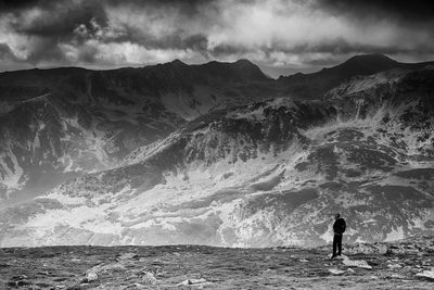 Rear view of man standing on mountain by sea against sky