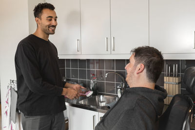 Smiling men talking in kitchen