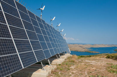 Solar panels on riverbank against clear sky