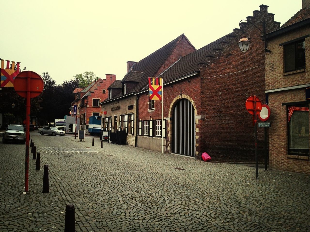 building exterior, architecture, built structure, street, clear sky, house, road, residential structure, cobblestone, the way forward, residential building, transportation, city, street light, incidental people, sky, outdoors, day, building, red