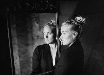 Thoughtful woman looking away while reflecting in mirror