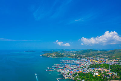 High angle view of sea by cityscape against blue sky