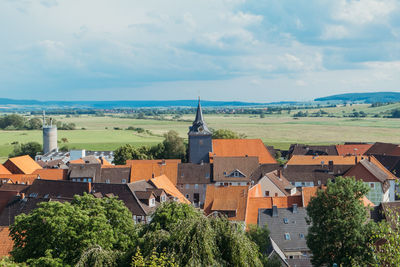 Aerial view on the roofs of a european village with a spire of a catholic church against a blue sky.