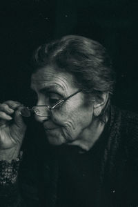 Close-up of senior woman looking away against black background