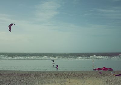 People on beach by sea against sky