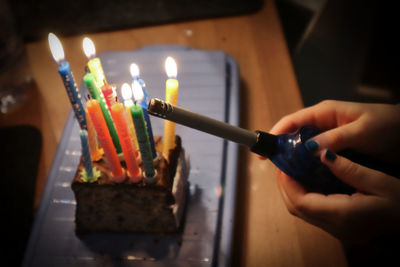 Close-up of hand holding light birthday candles with lighter