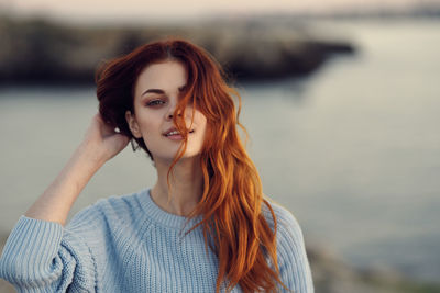 Portrait of young woman standing against lake