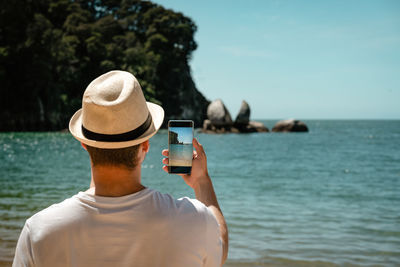 Rear view of person photographing sea