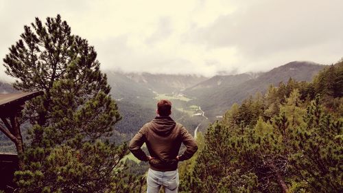 Rear view of man standing on mountain against sky