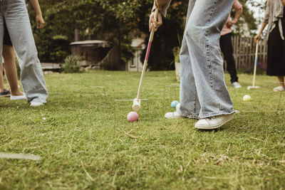 Low section of teenage girl playing polo with family in front yard