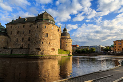  the castle by river against cloudy sky