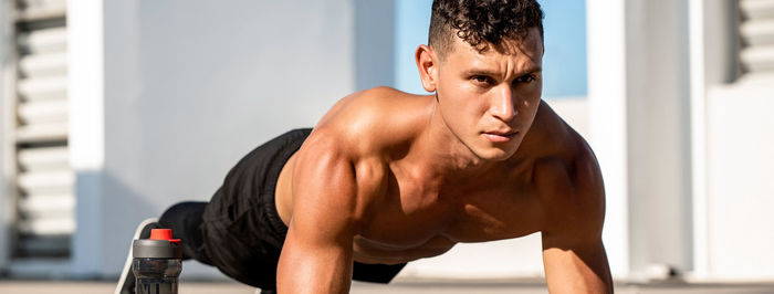 Young shirtless man exercising outdoors