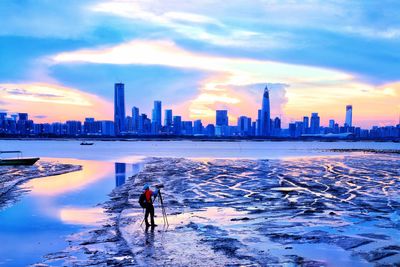 Man standing by sea against sky during sunset