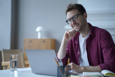 Smiling businessman using laptop while sitting at cafe