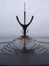 Close-up of metallic structure by sea against sky