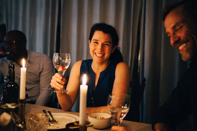 Happy woman enjoying dinner with male friends in party at home