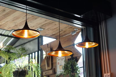 Low angle view of illuminated pendant lights hanging from ceiling