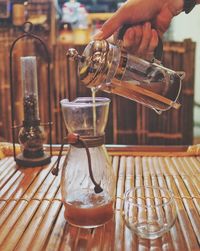 Cropped hand of woman pouring coffee into container on table